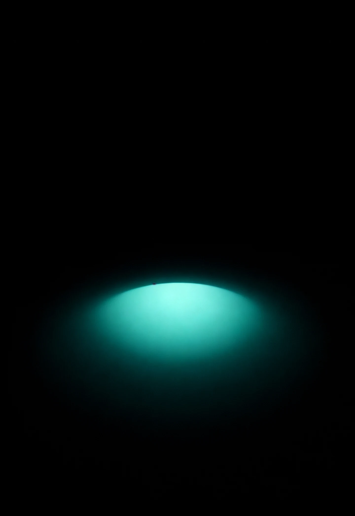 AMOLED & Dark wallpaper fitted to the iPhone Duo outer display — a gentle mint glow resting low on deep black, kept clear of every edge